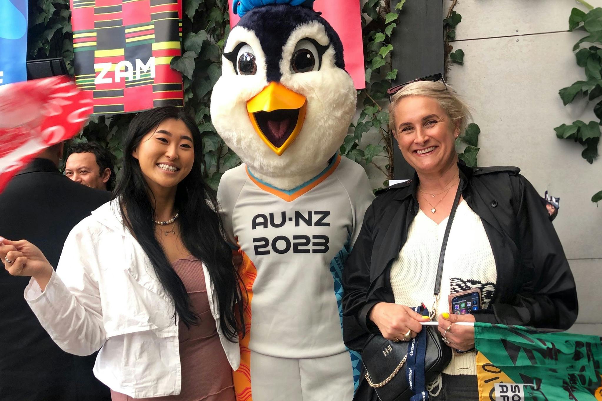 Two woman and the FIFA WWC mascot smile together